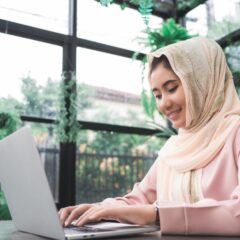 beautiful-young-smiling-asian-muslim-woman-working-laptop-sitting-living-room-home